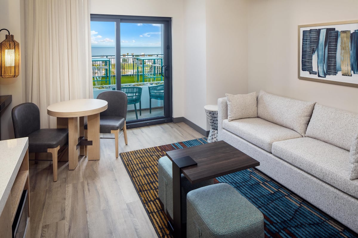 Ein modernes Hotelzimmer mit Balkon, Essbereich, Sofa und Couchtisch.