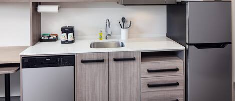 A modern kitchen with a dishwasher, microwave, refrigerator, and wooden cabinets.