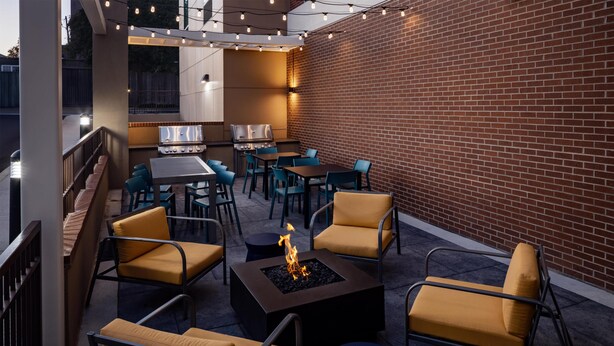 Un patio al aire libre con una chimenea, asientos y una parrilla.