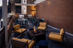 Eine Terrasse im Freien mit Feuerstelle, Sitzgelegenheiten und Grill.