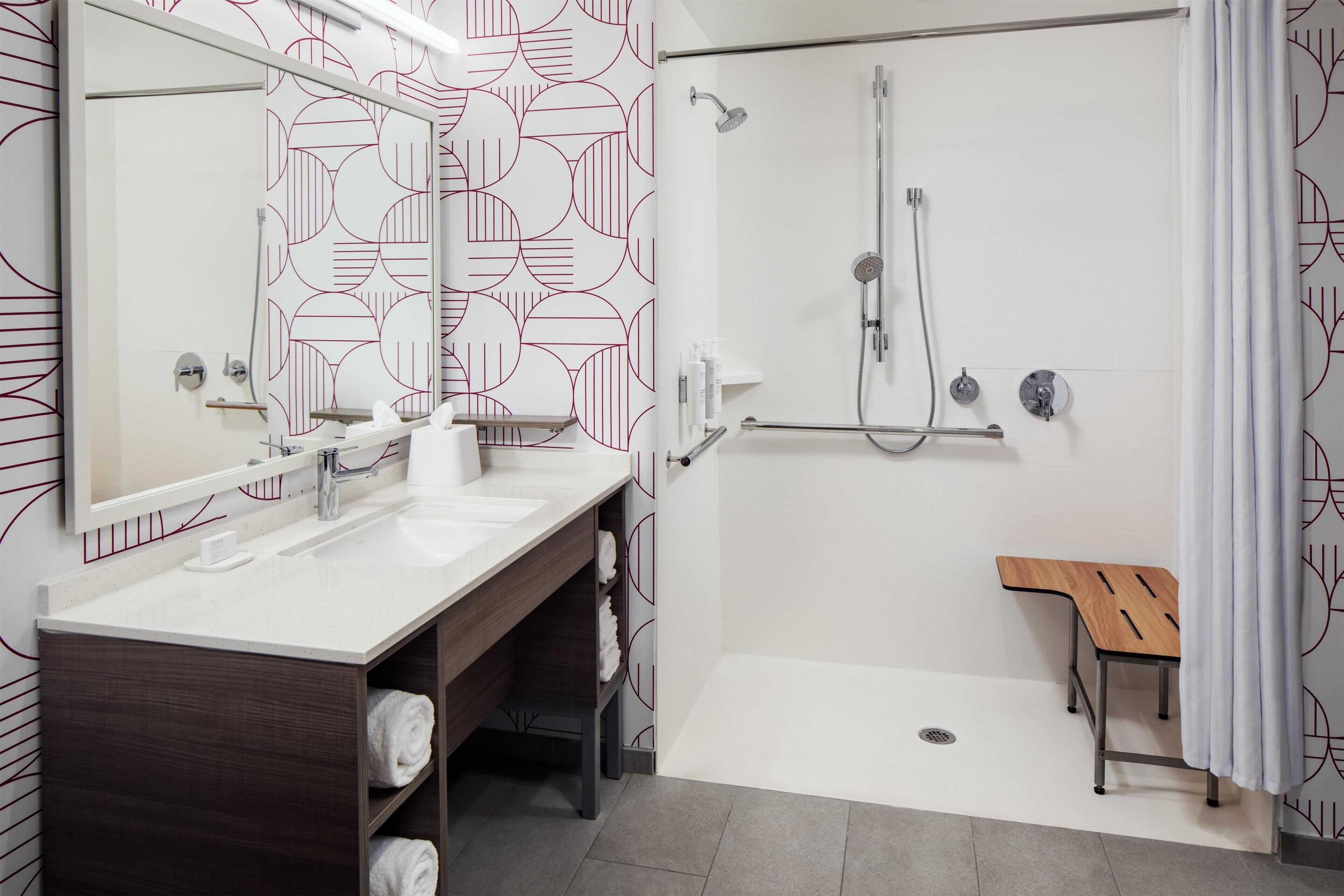 A modern bathroom with a shower, two sinks, a vanity, and a wooden bench.