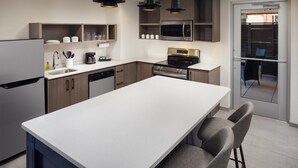 Una cocina moderna con una isla central, electrodomésticos integrados e iluminación colgante.
