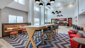 A spacious lobby with a long wooden table, multiple seating areas, and a patterned carpet. - Hampton Inn & Suites By Hilton Louisville East Oxmoor (Louisville)