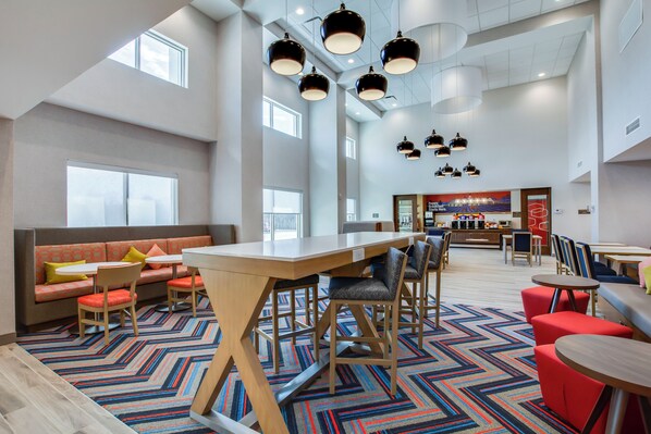 A spacious lobby with a long wooden table, multiple seating areas, and a patterned carpet. - Hampton Inn & Suites By Hilton Louisville East Oxmoor (Louisville)