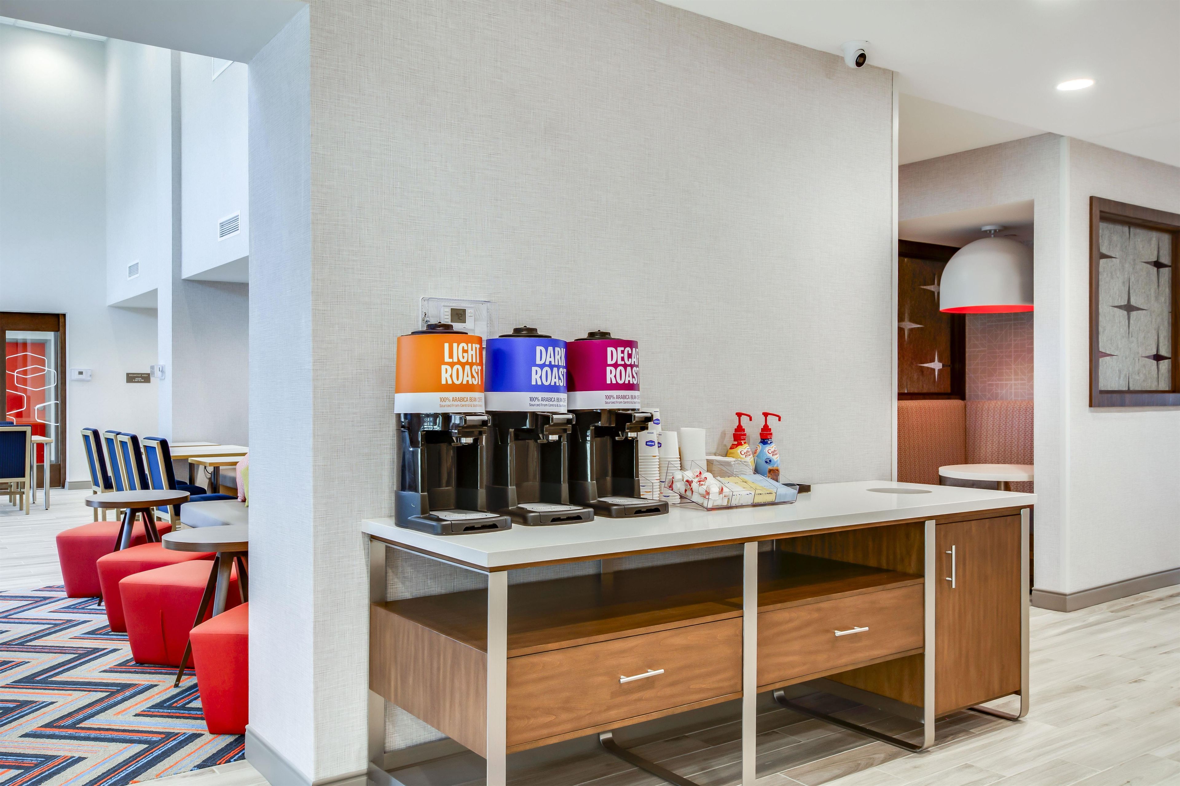 Un distributeur de café moderne doté de trois réservoirs, étiquetés respectivement « café léger », « café corsé » et « café décaféiné ».