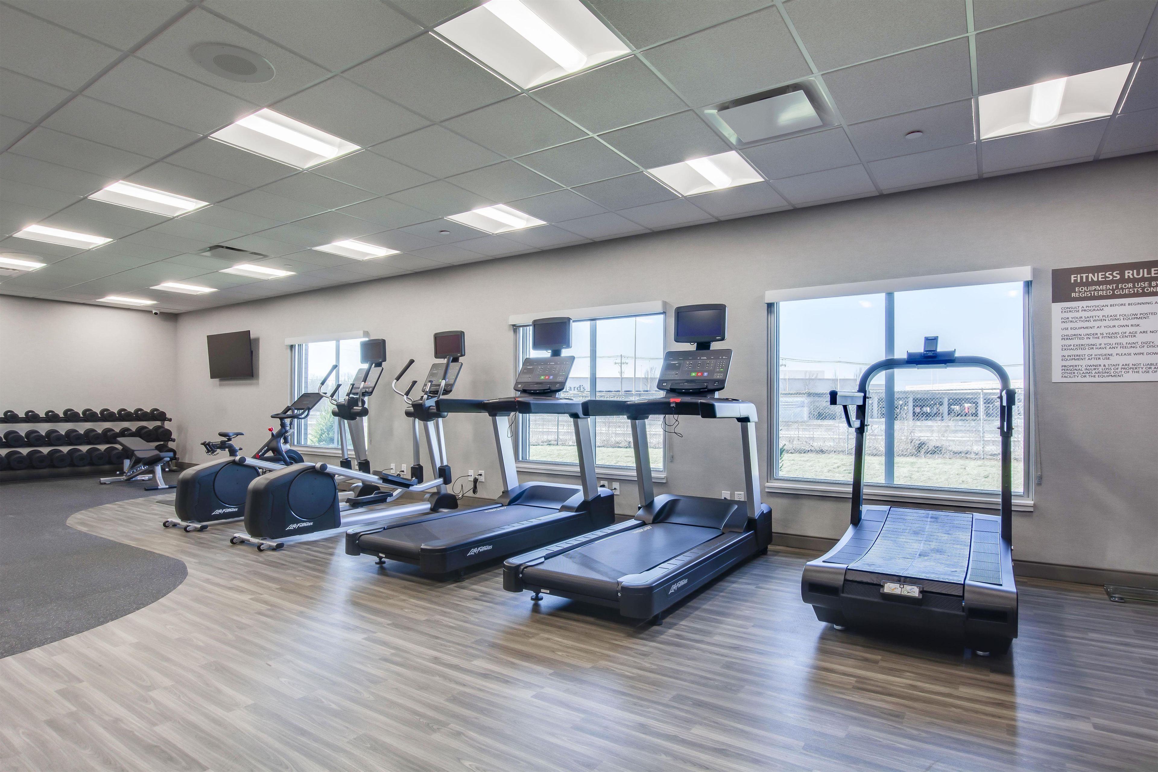 A gym with treadmills, elliptical machines, and weight benches.
