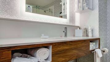 Un baño moderno con un espejo grande, tocador de madera y azulejos con diseño.