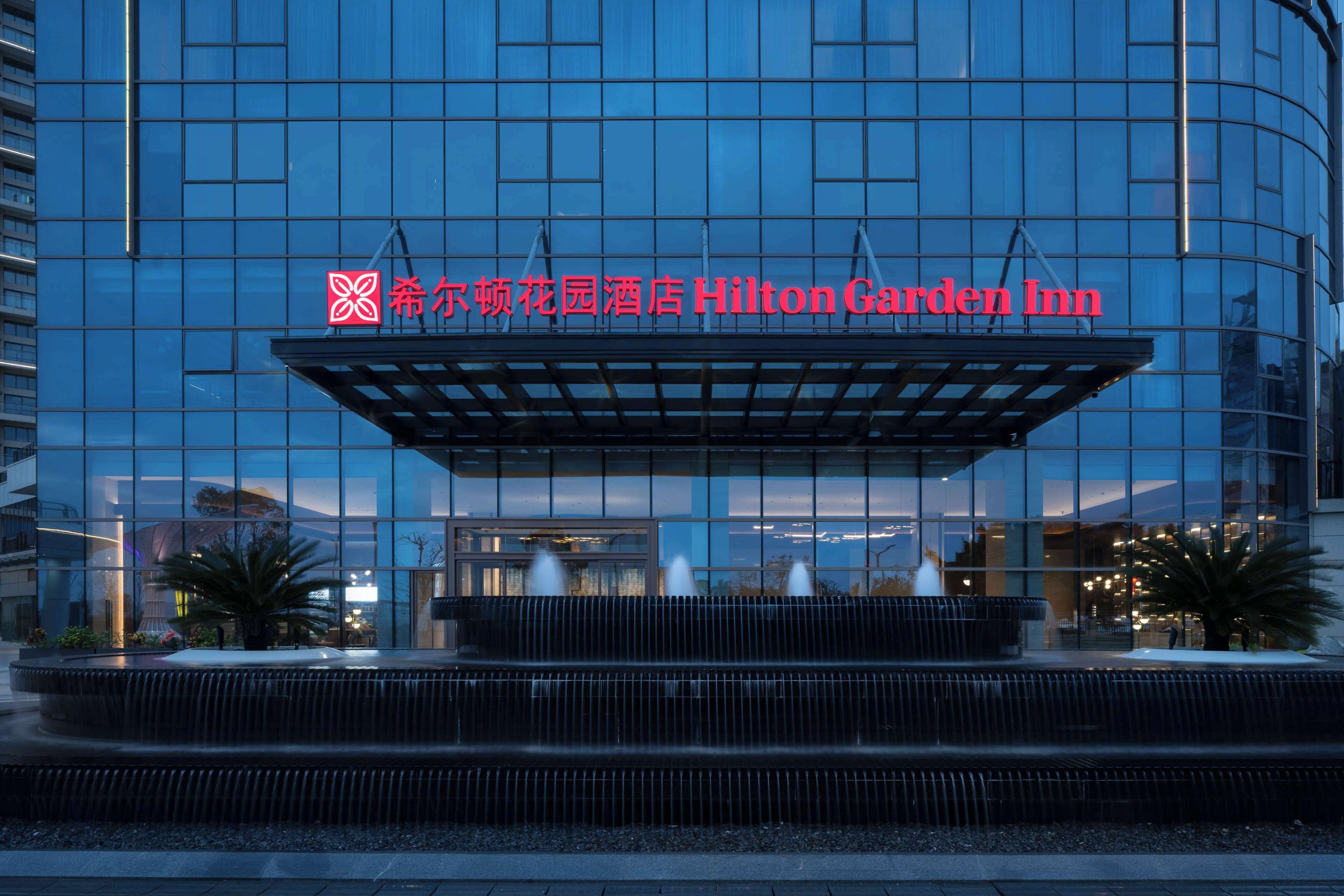 A modern building with a large glass facade and a prominent sign for Hilton Garden Inn.