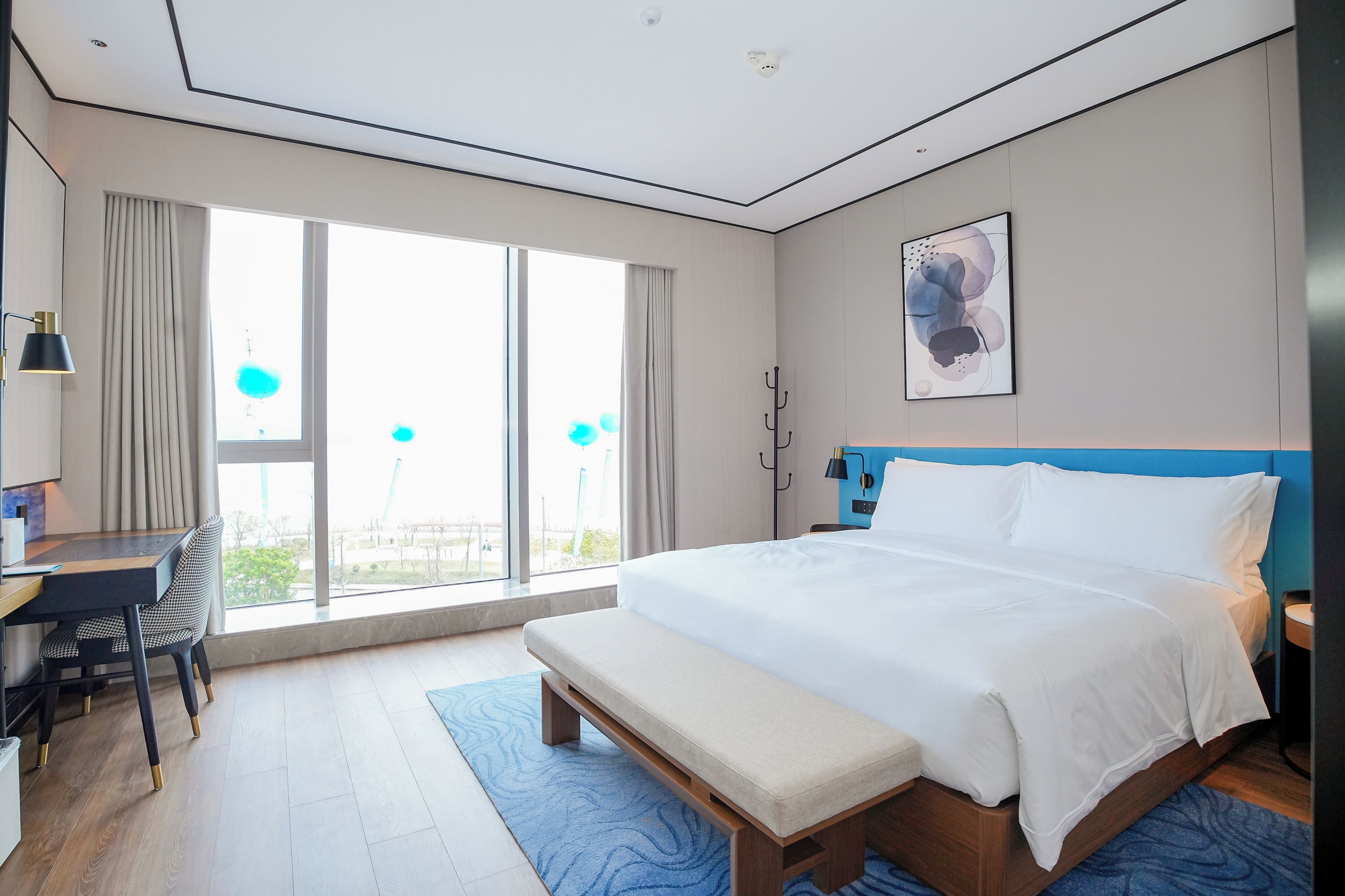 Habitación de hotel moderna con una cama grande, un escritorio y vistas al exterior.
