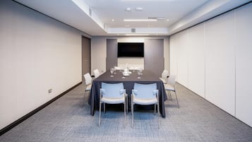 A conference room with a long table, chairs, and a flat-screen TV.