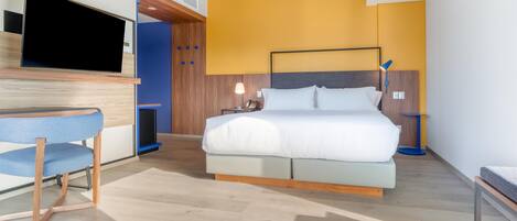 Une chambre d’hôtel moderne équipée d’un lit, d’un bureau, d’une chaise et d’un téléviseur.