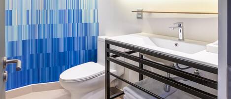 A modern bathroom with a toilet, a sink with a mirror above, and a towel rack with folded towels.