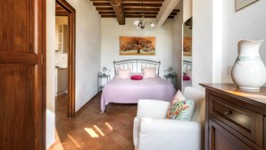 A bedroom with a bed, a chair, a dresser, and a painting on the wall.