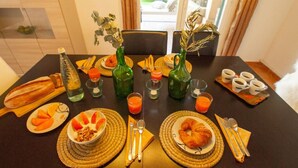 Une table de petit-déjeuner dressée avec du pain, des fruits, un croissant et des boissons.