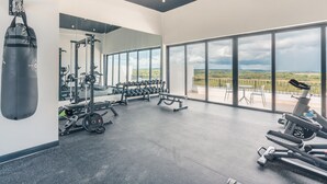 A gym with a punching bag, weight machines, dumbbells, and a treadmill. - Cozy 1BR w Balcony Pool Beach Access Cap Cana (Punta Cana)