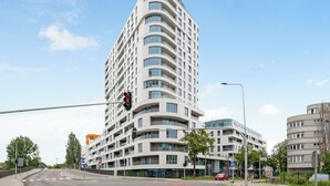 A modern high-rise hotel with multiple balconies, a curved facade, and a prominent corner location. - Studio Sw. Piotra by Grand Apartments (Gdynia)