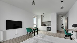 A modern hotel room with a large bed, a TV, a desk, and a kitchenette. - Studio Sw. Piotra by Grand Apartments (Gdynia)