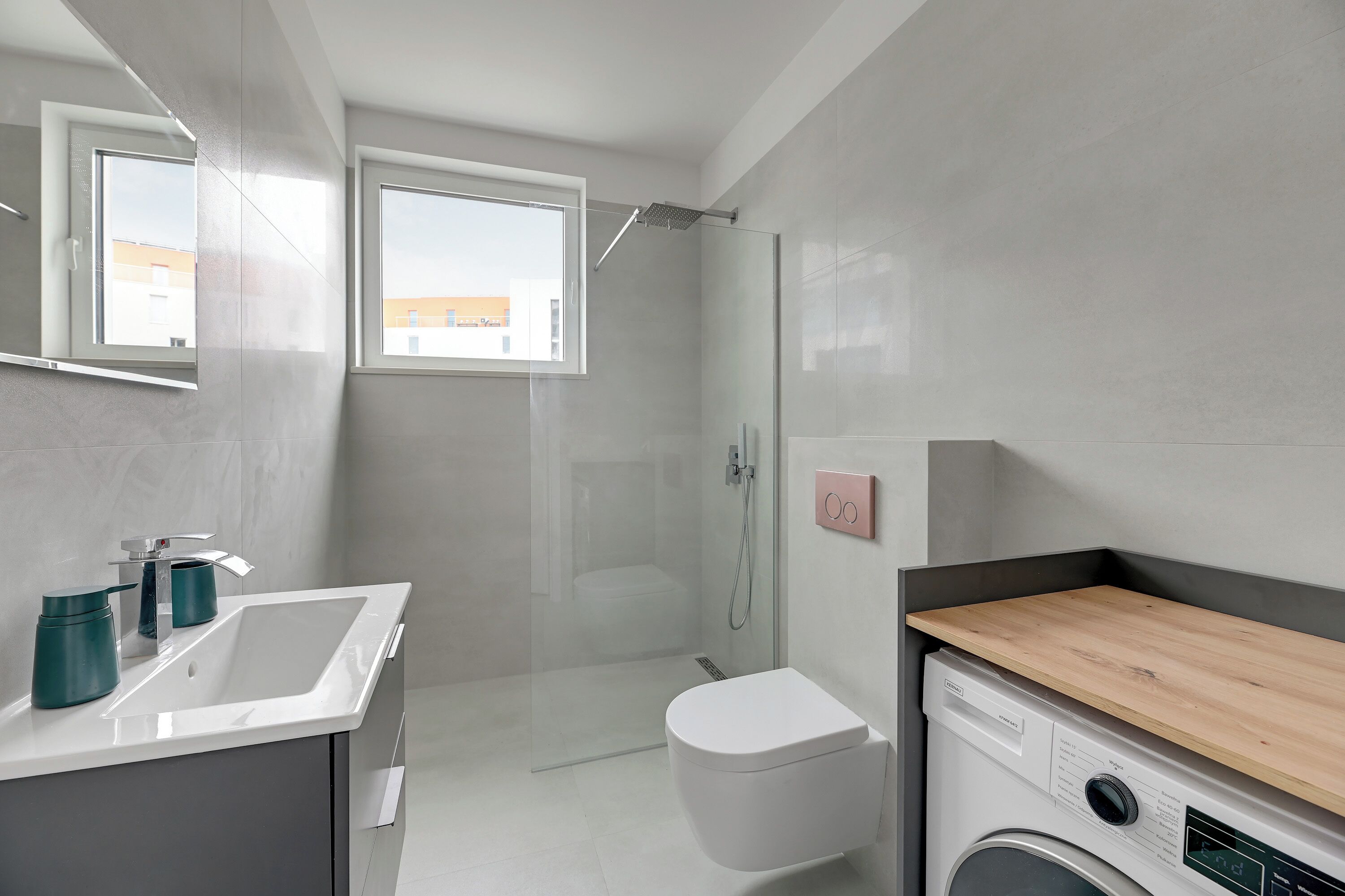 A modern bathroom with a shower, toilet, sink, and a built-in washing machine.