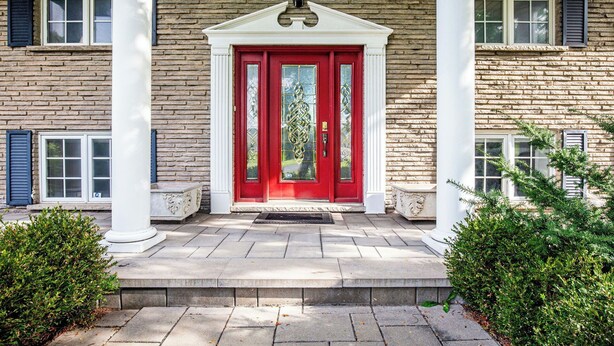 Un edificio de ladrillo con puerta roja, columnas blancas y entrada de piedra.