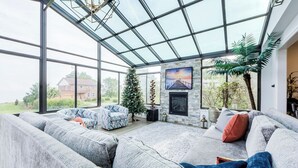 Un salon spacieux doté d’un grand plafond en verre, d’une cheminée et d’un coin salon confortable.
