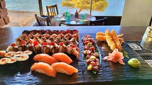 A sushi platter with various types of sushi on a table, with a view of a harbor and buildings in the background. - Villa del Artista super lujo (Llucmajor)