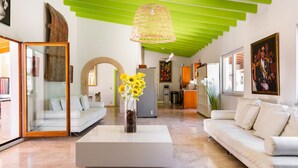 A modern living room with a white sofa, a coffee table with a vase of sunflowers, and a green ceiling. - Villa del Artista super lujo (Llucmajor)