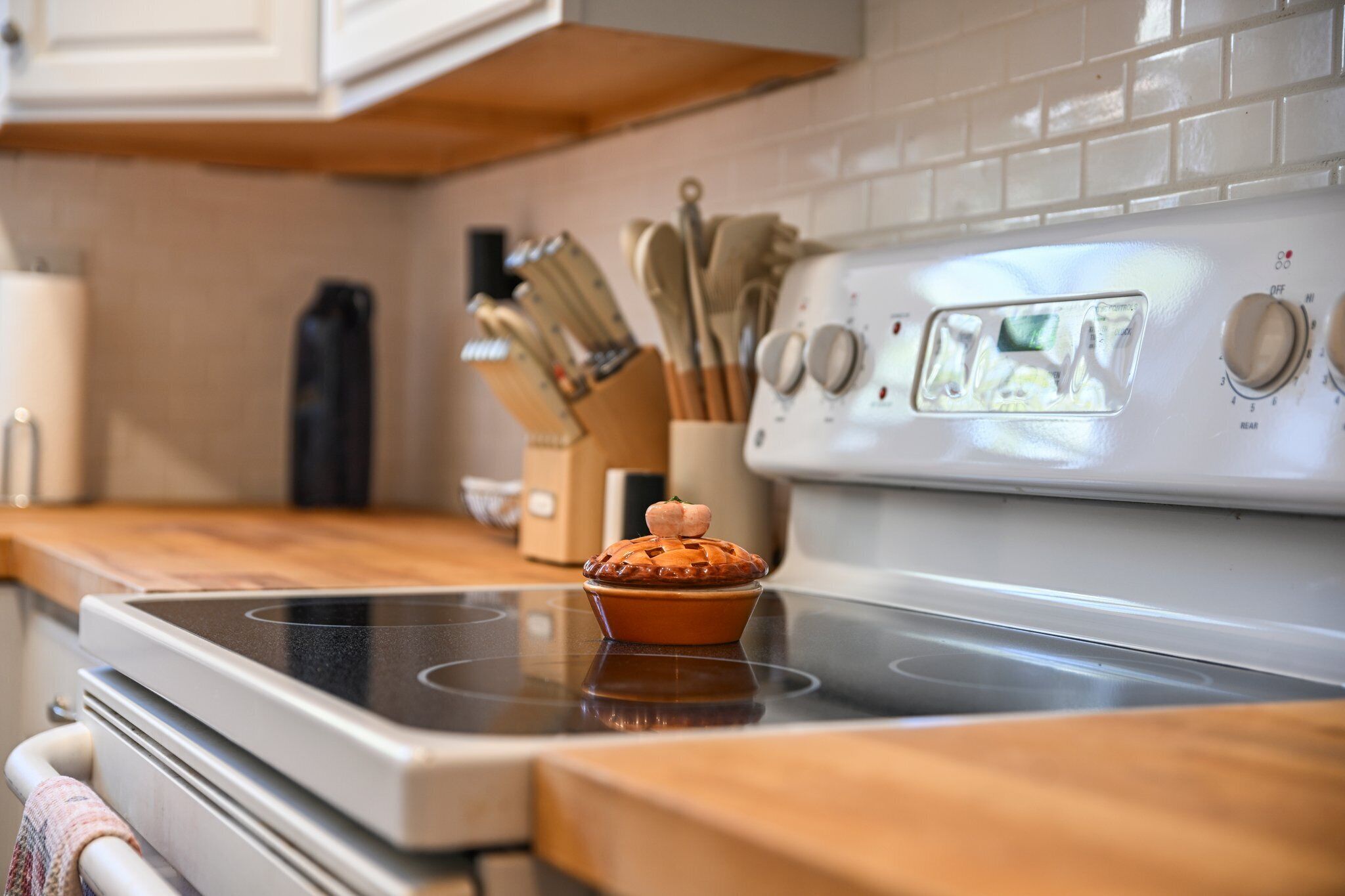 A kitchen with a stove, a muffin on the stove, and a knife block in the background.