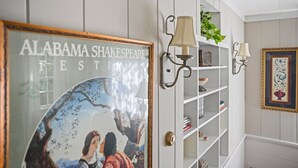 Een gang met een lijst met het 'Alabama Shakespeare Festival', een witte wandplank met decoratieve objecten, en wandlampen.