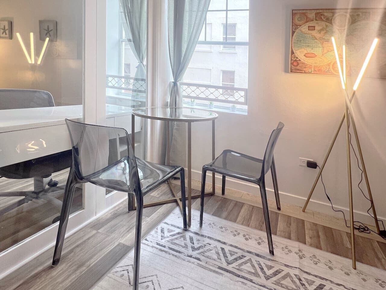A modern room with a glass table and chairs, a white piano, and a floor lamp.