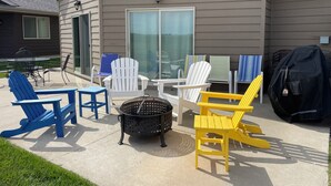 Eine Terrasse mit Gartenmöbeln, darunter Stühle, ein Tisch und ein Grill.