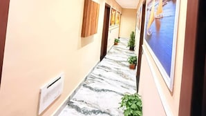 A hallway with a marble floor, potted plants, and framed artwork on the walls. - Olivia Hotel (Cairo)