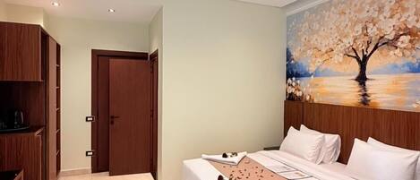 Quarto com cama, guarda-roupa de madeira e pintura de uma árvore.