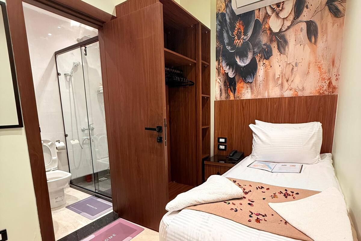 Ein Hotelzimmer mit einem Bett, einem Holzschrank, einer Dusche und einer Wandklimaanlage.
