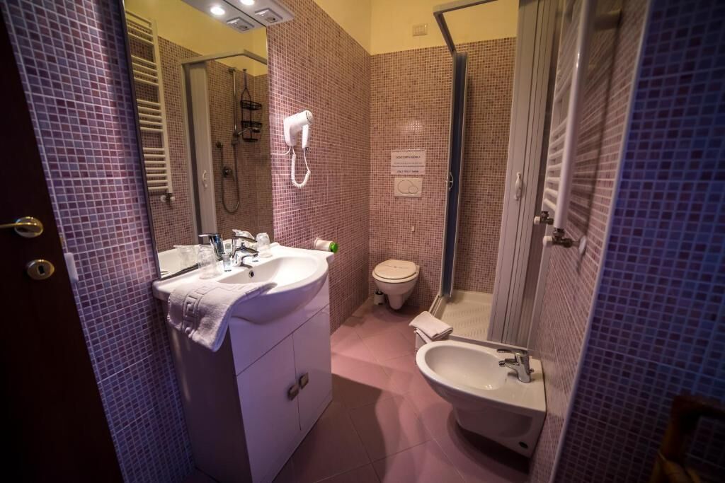 A bathroom with a sink, toilet, bidet, and a shower area.