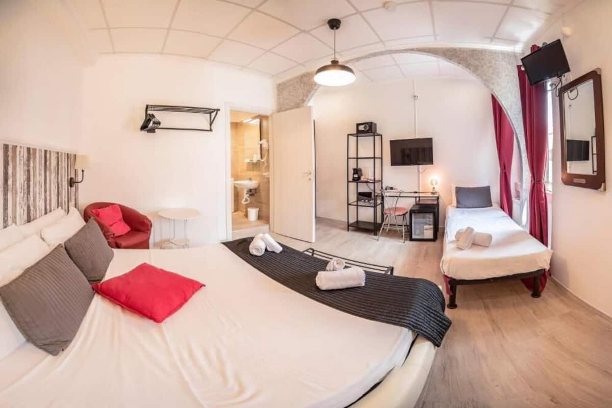 A hotel room with a large bed, a desk, a chair, a TV, and a mirror.