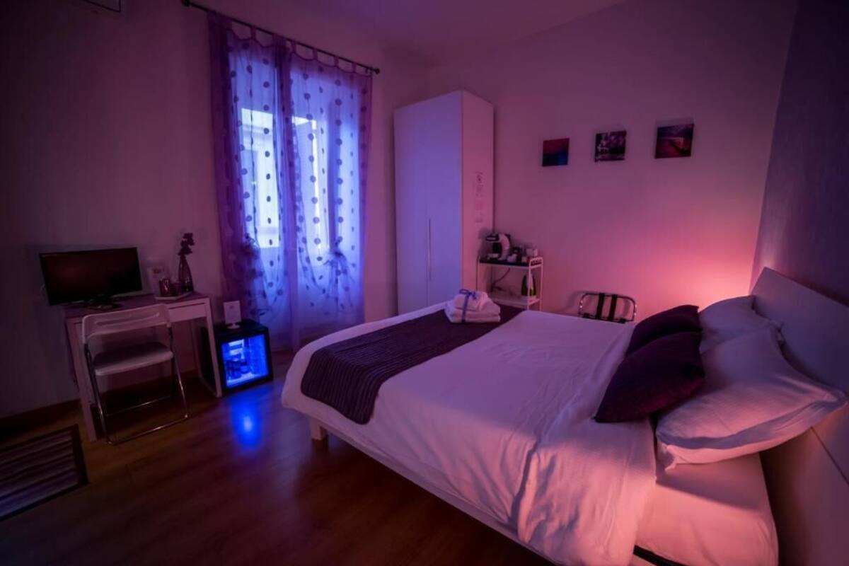 A bedroom with a bed, a desk, a wardrobe, and a window with curtains.