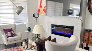 A modern living room with a fireplace, comfortable seating, and a television.