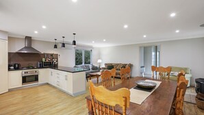 Eine moderne Küche mit weißen Schränken, einem eingebauten Backofen und einem Essbereich mit Holztisch und Stühlen.