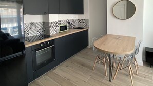 A modern kitchen with black cabinets, a wooden countertop, and a round dining table with chairs.