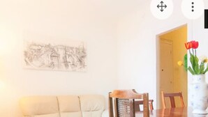 A dining area with a wooden table, chairs, a white sofa, and a wall-mounted painting. - Private room (1) near the University with large terrace of 150 m2.  (Barcelona)