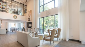 A spacious living area with a sofa, chairs, a dining table, and a large window offering a view of the outdoors. - Landing at Crestline (Birmingham)