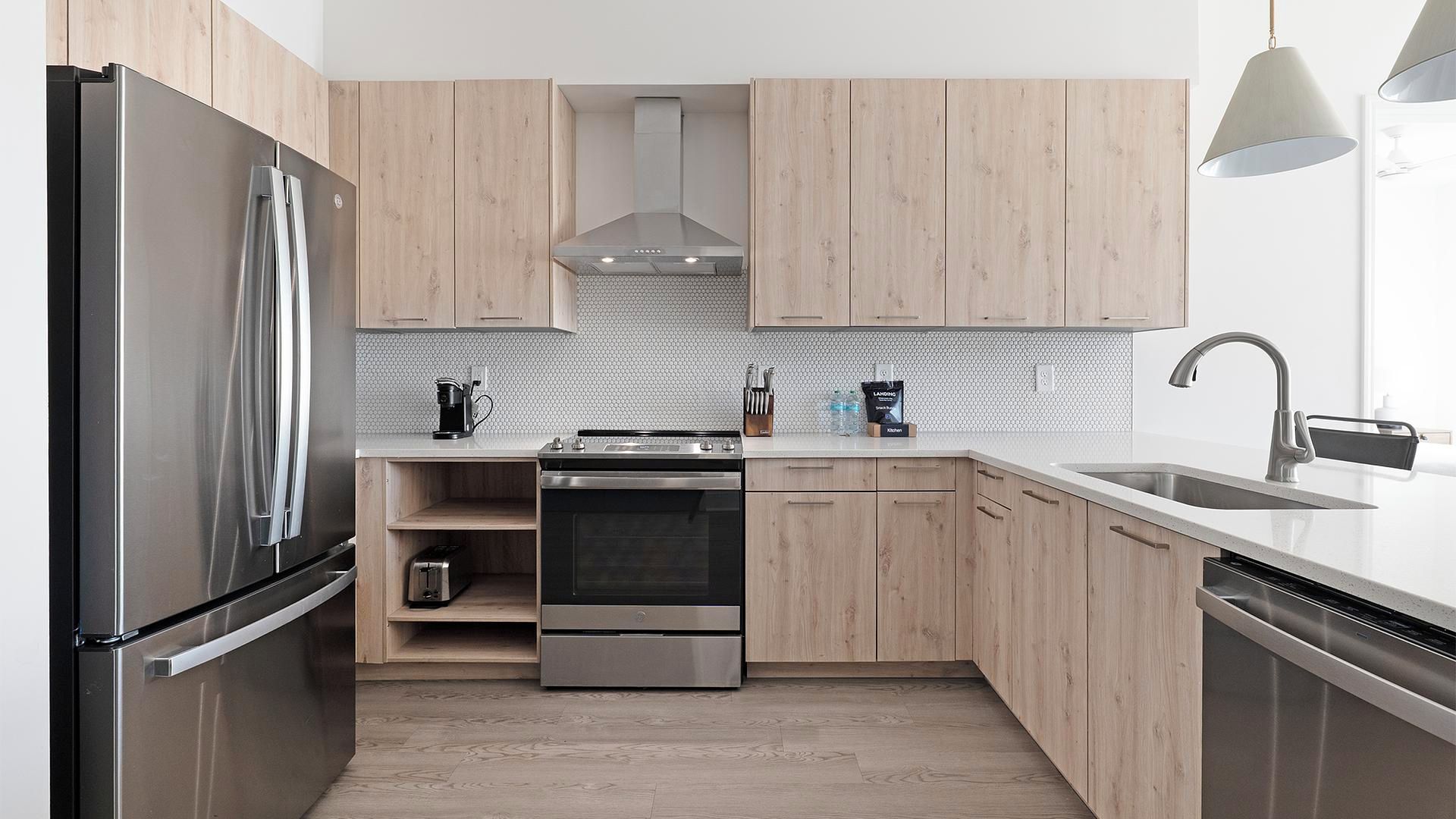 Una cucina moderna con elettrodomestici in acciaio inossidabile, mobili in legno, forno a incasso e lavello.