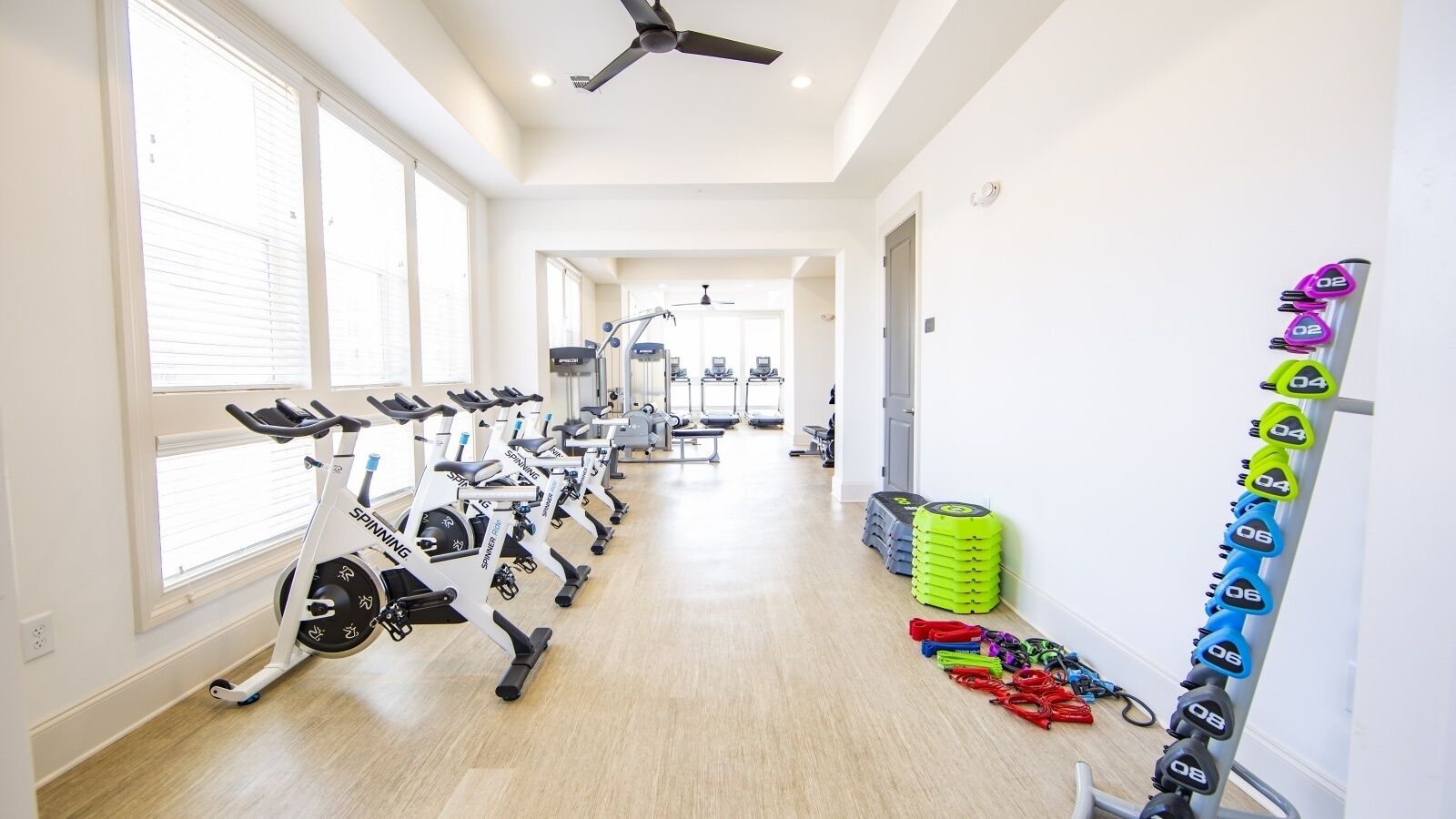 A gym with stationary bikes, weight machines, and a variety of weights on racks.