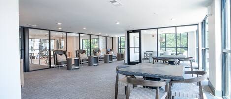 A modern conference room with glass walls, a marble table, and comfortable seating.
