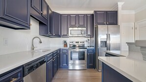 A modern kitchen with dark cabinets, stainless steel appliances, and a dishwasher. - Cary Apartments by Landing (Cary)