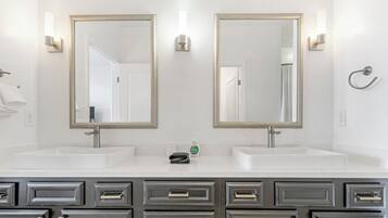 A bathroom with two sinks, two mirrors, and a towel rack.
