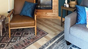 Un salon chaleureux avec un mur en bois, une cheminée et deux fauteuils.