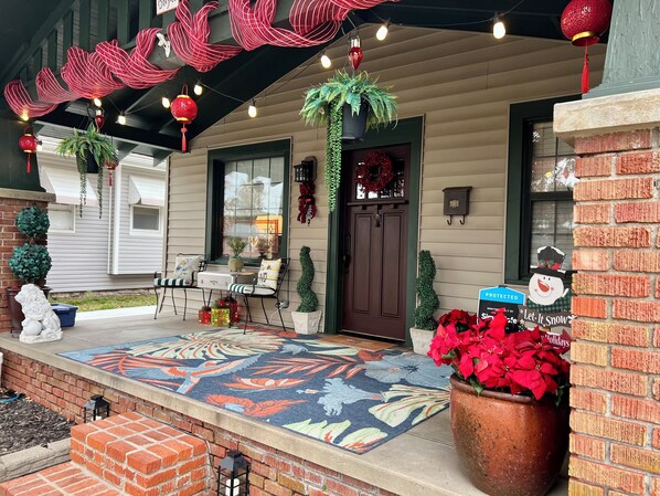 A decorated porch with a patterned rug, potted plants, and a sign indicating a promotion.