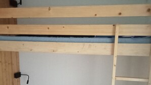 Una cama litera con escalera y un enchufe en la pared.