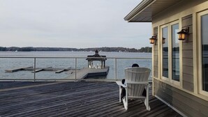 Eine Holzterrasse mit Seeblick, einem Pavillon und einem Stuhl.